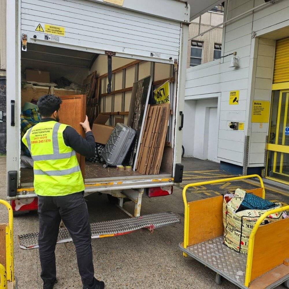 Mover loading furniture and boxes into a removal truck as part of secure packing and transport service in North London.