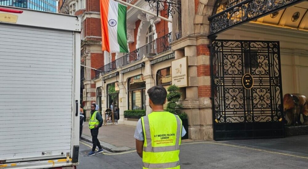 Team from 24/7 Movers Packers London outside Taj Hotel London near Indian flag, ready to perform premium relocation services with moving truck parked by the entrance.