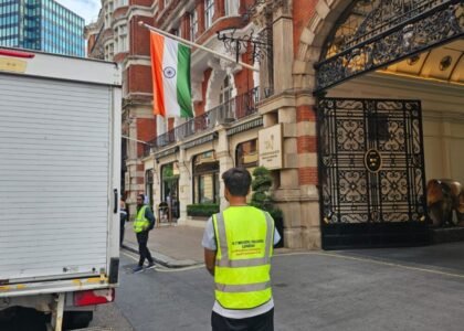Team from 24/7 Movers Packers London outside Taj Hotel London near Indian flag, ready to perform premium relocation services with moving truck parked by the entrance.