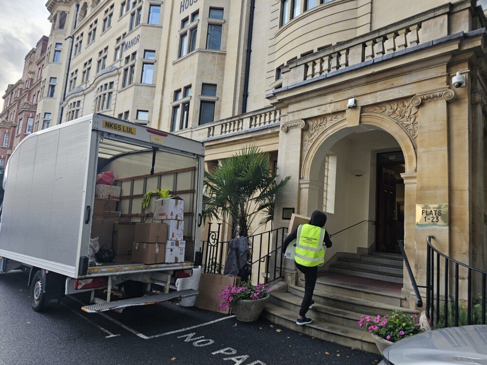 24/7 Movers Packers London team unloading packed boxes from a moving van outside a London apartment building, preparing for a flat relocation.